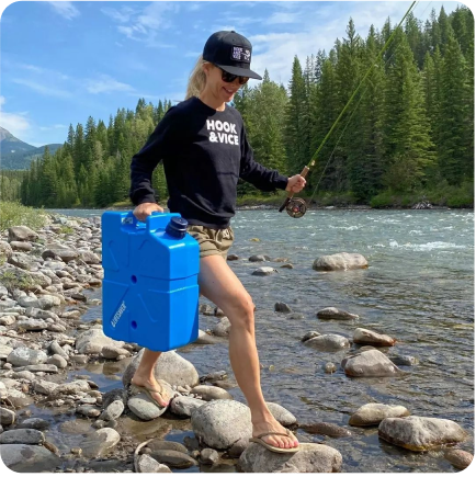 Woman with a fishing rod making her way to the river edge to fill her LifeSaver Jerrycan